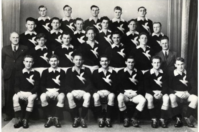 A group of men fold their arms and look at the camera.
