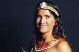 Young Aboriginal woman with white ochre dot painting under her eyes and over collarbone wearing woven grass headband with shell