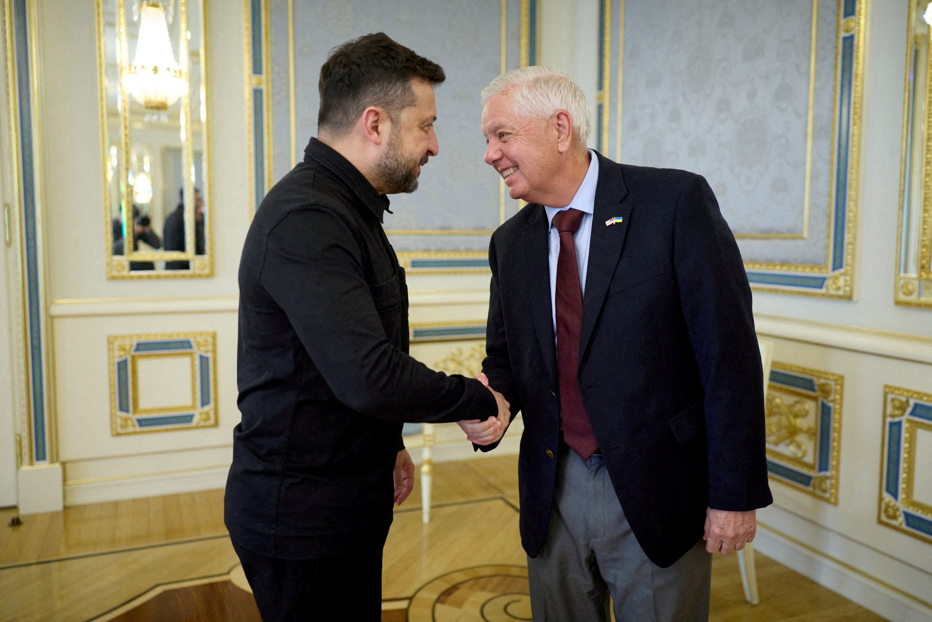 Volodymyr Zelenskyy shakes hands with a smiling Lindsey Graham