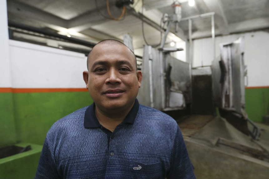 A man poses in front of an empty metal cattle-restraint box inside an empty abattoir.