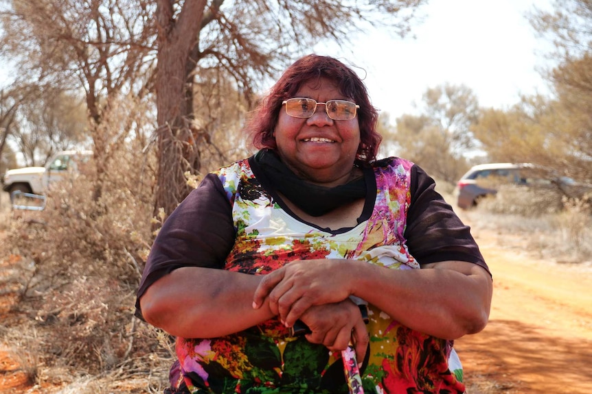 A woman sitting under a tree smiling at the camera.