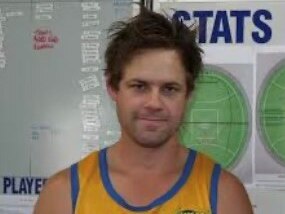 A photo of a young man in an Aussie Rules football shirt, seemingly after playing a game.