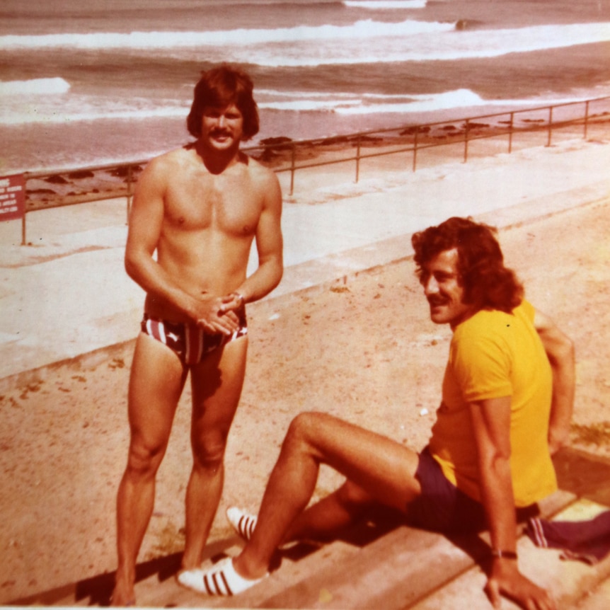 A shirtless Ken Holloway stands on a Jersey beach with a friend.