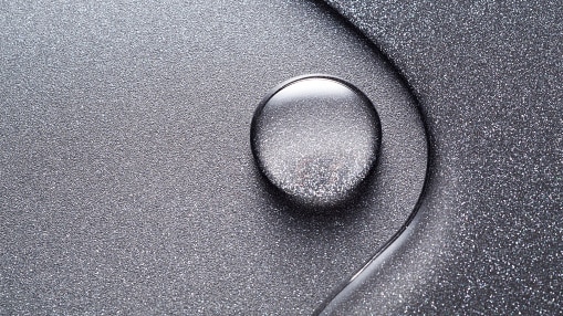 From above, you view an abstraction of a teflon-coated surface, with water droplets floating on it.