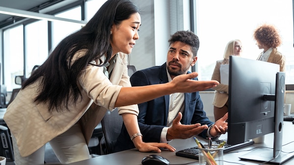 In the office, displeased female CEO of Asian ethnicity, scolding her male mixed-race employee.