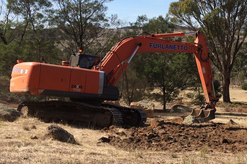 A digger digs up a rabbit warren on a property in the Victorian Mallee.