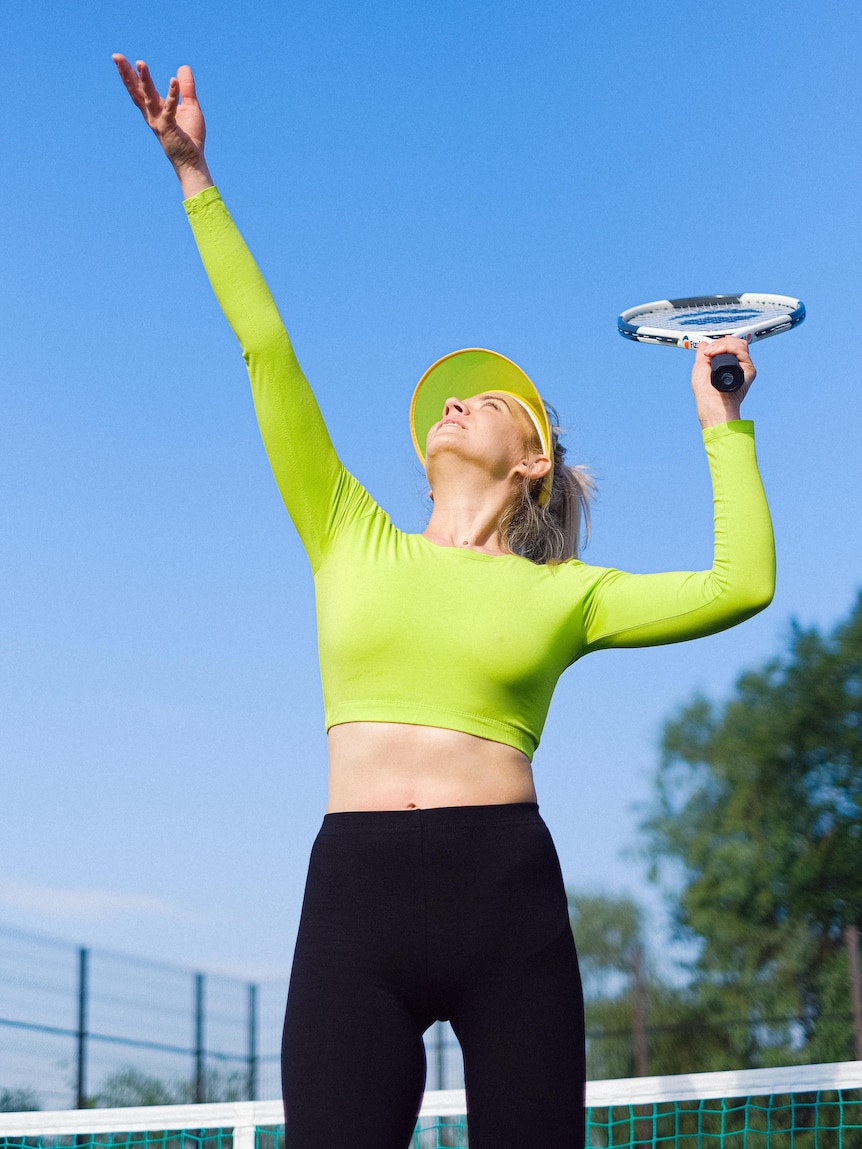 A woman throwing the ball high in the air to serve in tennis.