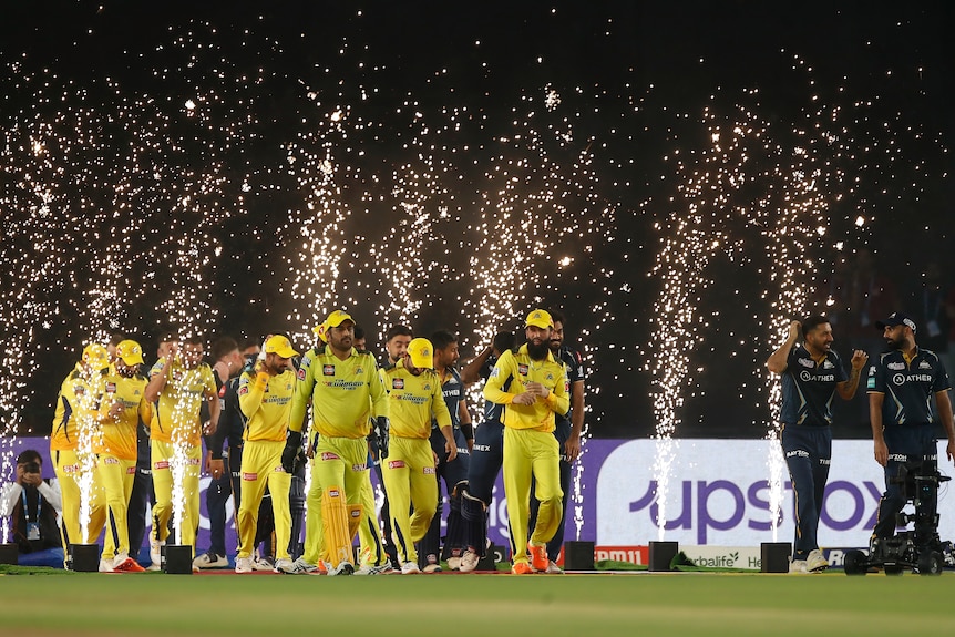 Players walk out in front of sparklers at the IPL