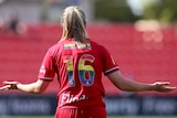 A soccer player wearing a red jersey with rainbow numbers