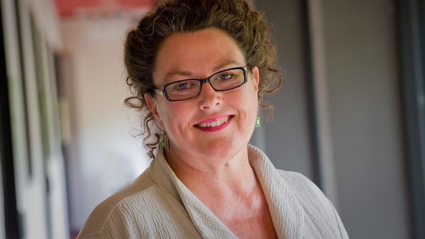 A head and shoulders shot of a smiling woman wearing spectacles posing for a photo.