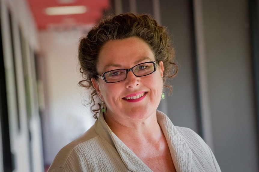 A head and shoulders shot of a smiling woman wearing spectacles posing for a photo.