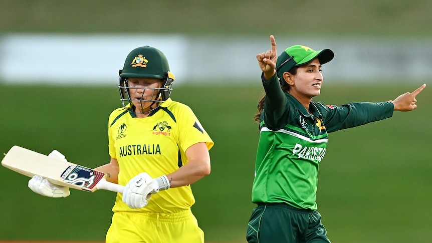 Omaima Sohail points with both arms out stretched as she celebrates the wicket of Alyssa Healy who looks down as she walks off