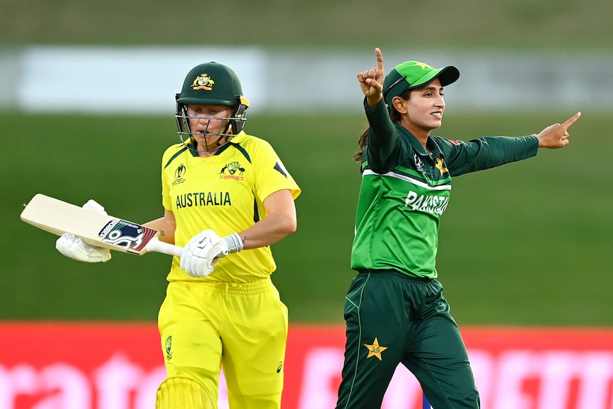 Omaima Sohail points with both arms out stretched as she celebrates the wicket of Alyssa Healy who looks down as she walks off