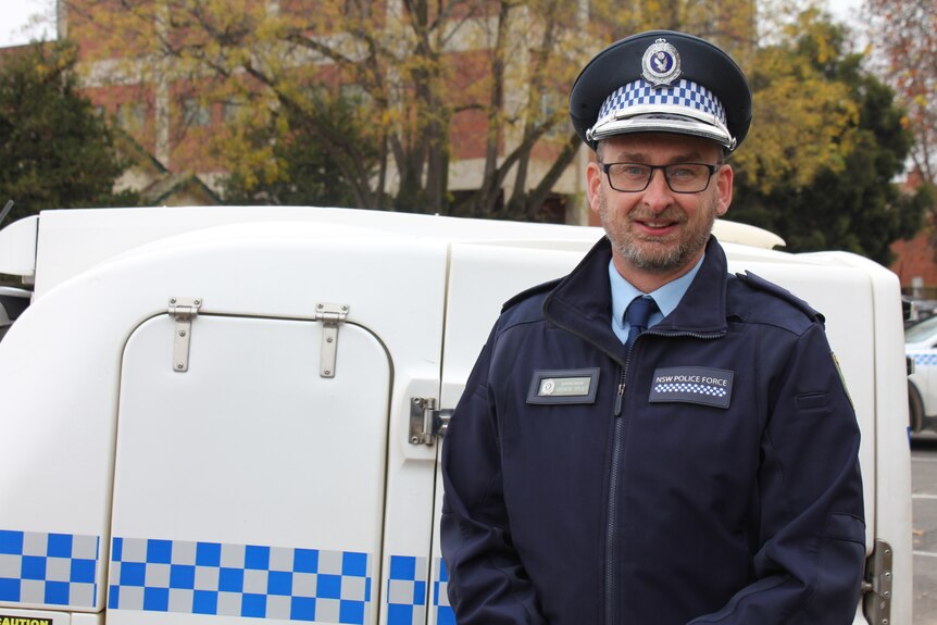 A male officer standing in front of a police van.