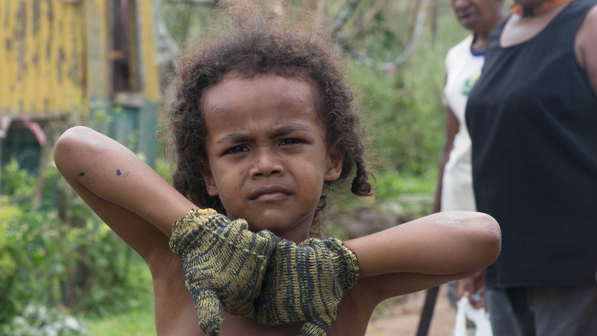A child helps with the clean-up after Cyclone Pam