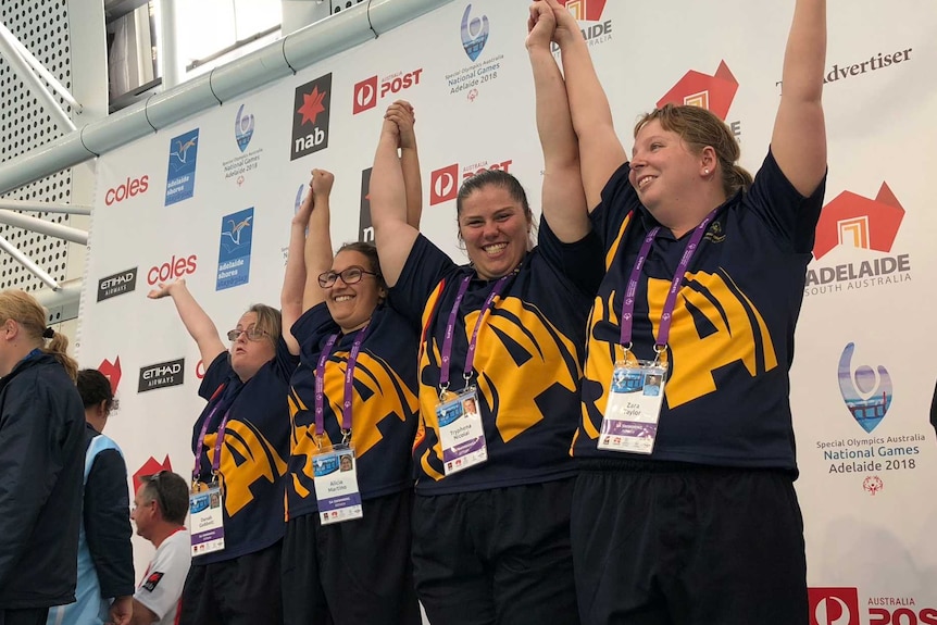 South Australian swimming team put their hands up on the podium after winning gold.