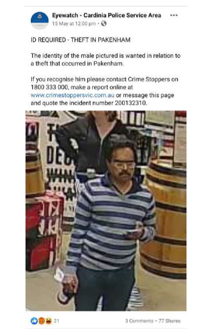 A man in a striped top walks through a bottle shop holding a bottle.