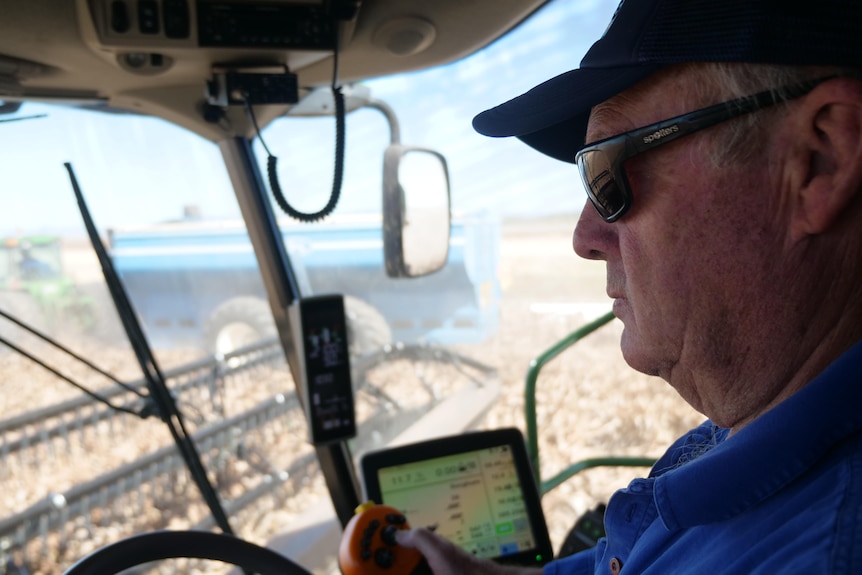 A man in a header with chaser bin visible through window