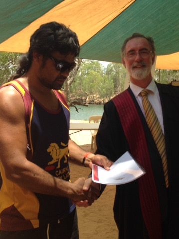 Two men shake hands at open air ceremony.