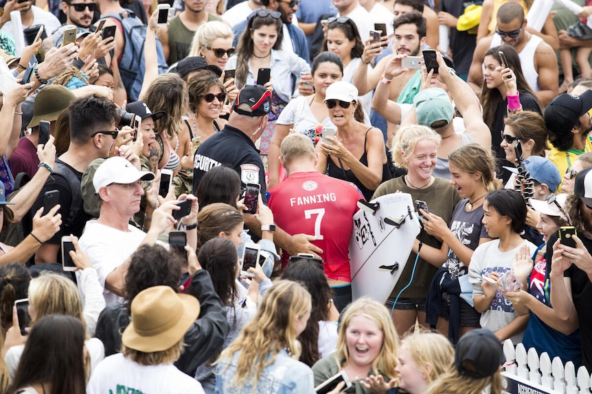 Mick Fanning works his way through the crowd of fans on the beach