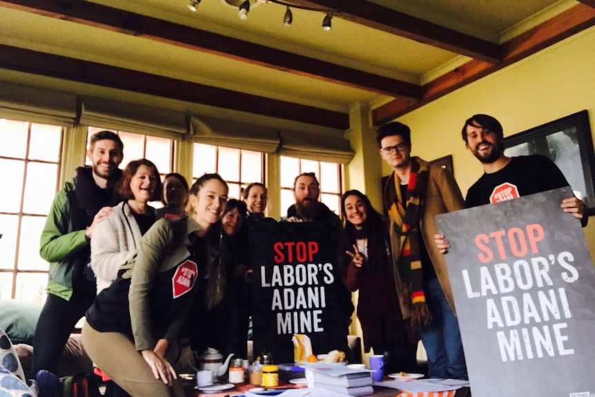 A group of people hold up Stop Labor's Adani Mine placards.