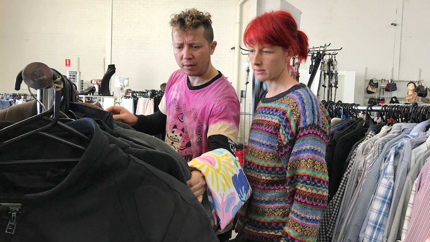 Christian Olea and Bex Frost look through a rack of jackets at an op shop.