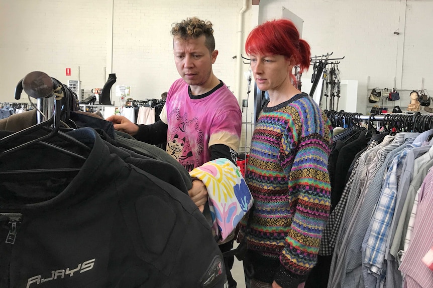 Christian Olea and Bex Frost look through a rack of jackets at an op shop.