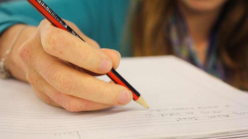 Up close shot of a hand writing on paper with a pencil.