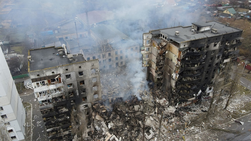Aerial photo showing destroyed apartment building, the centre of which is smoking rubble.