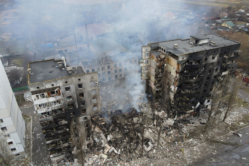 Aerial photo showing destroyed apartment building, the centre of which is smoking rubble.