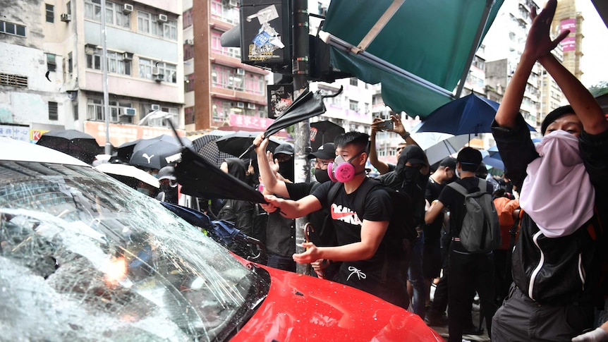 Protesters smash the window of a taxi with umbrellas  in Hong Kong.