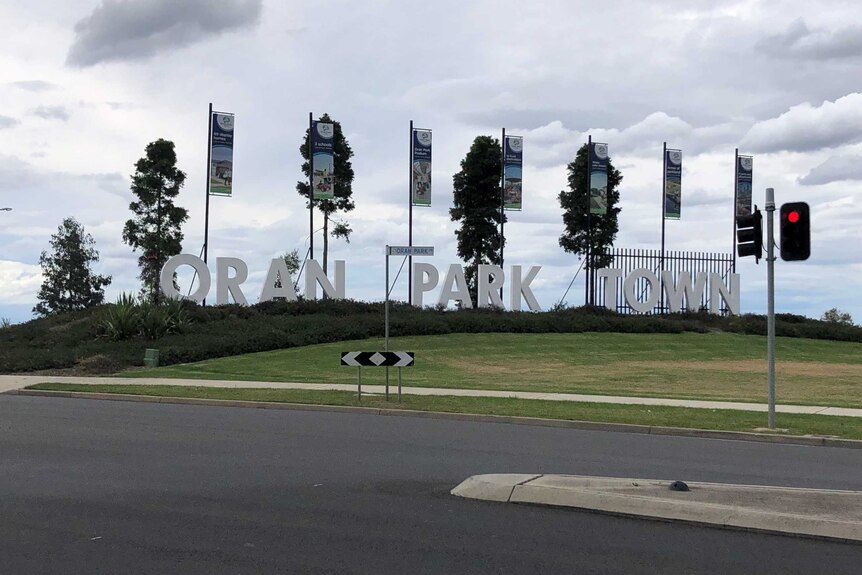 Oran Park Town sign on a grassy area, traffic light in foreground
