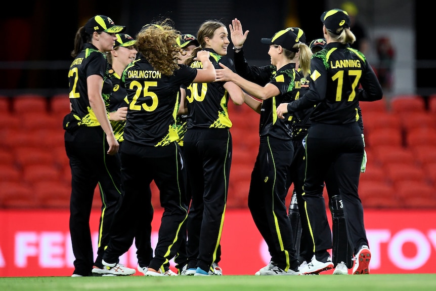 A group of Australian female cricketers celebrate a wicket against India.