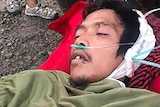 Jari Abdullah lies on the ground with oxygen tubes in his nose and bandages on his head.