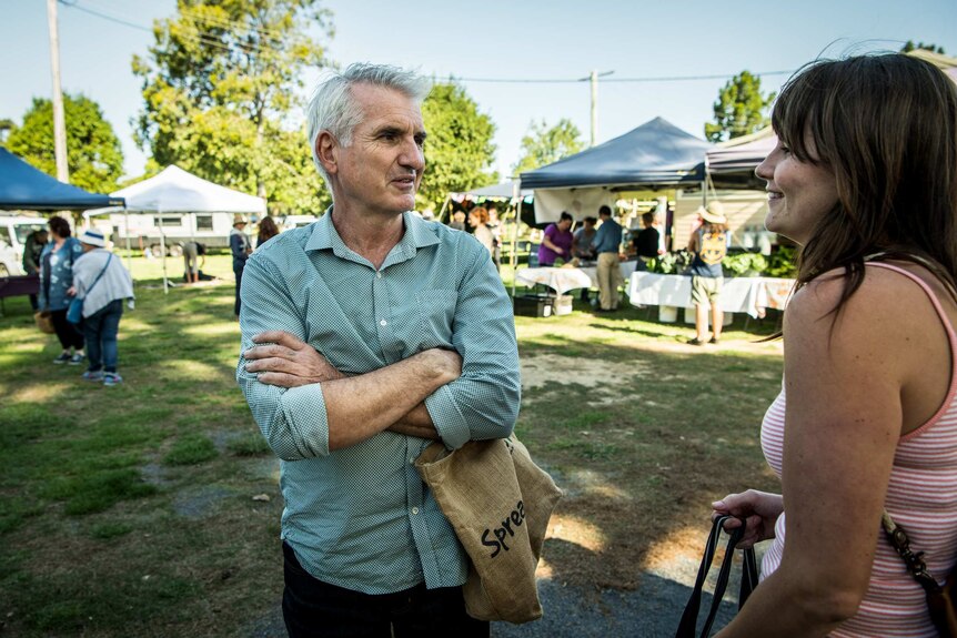 An older man chats to a resident at the local farmers market.