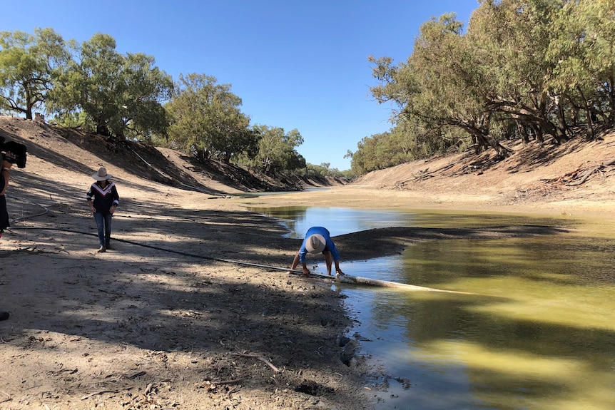 Bill and Chrissie Ashby of Trevallyn Station near Tilpa move a pump to a larger waterhole in the river.
