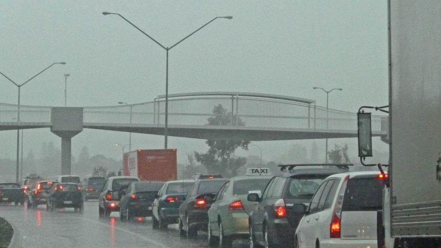 A line of traffic with cars' red lights as rain pours down on the freeway in Perth