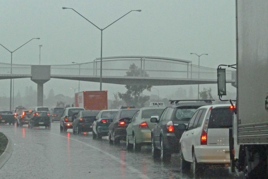 A line of traffic with cars' red lights as rain pours down on the freeway in Perth