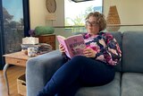 woman reads book on couch 