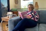 woman reads book on couch 