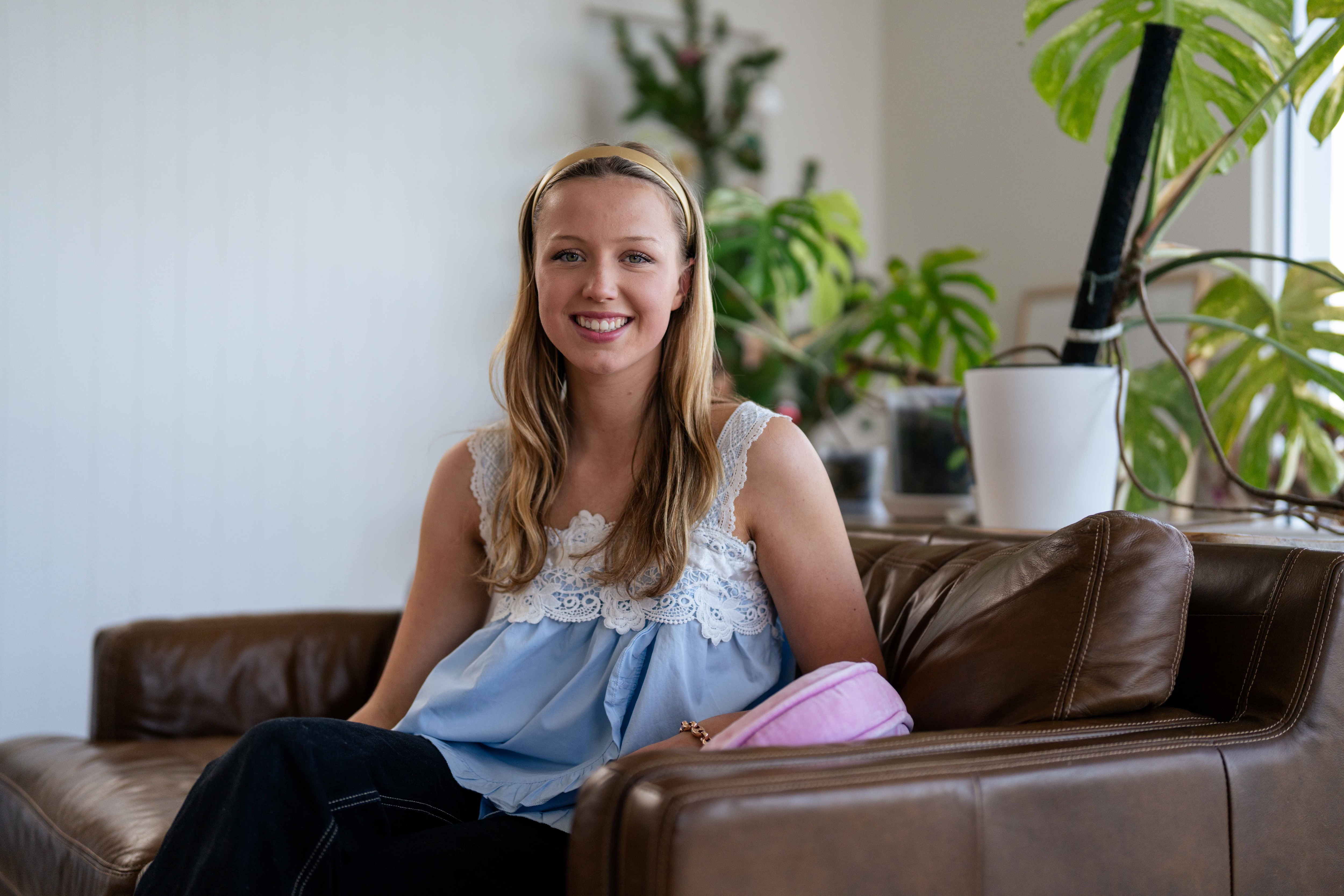 La mujer se sienta en el sofá y sonríe para una foto.