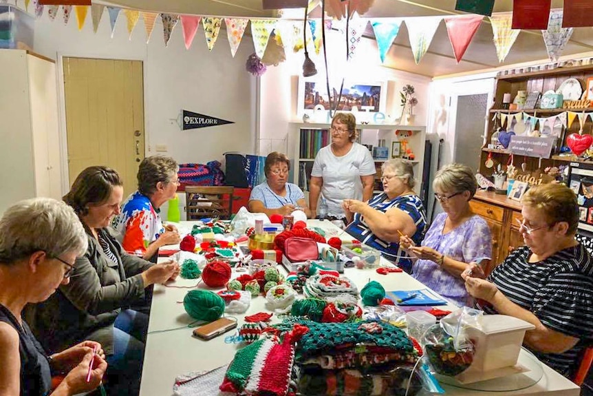 A group of ladies crocheting under bunting.