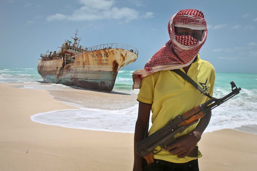 A pirate stands near a fishing vessel that washed ashore in Hobyo, Somalia.
