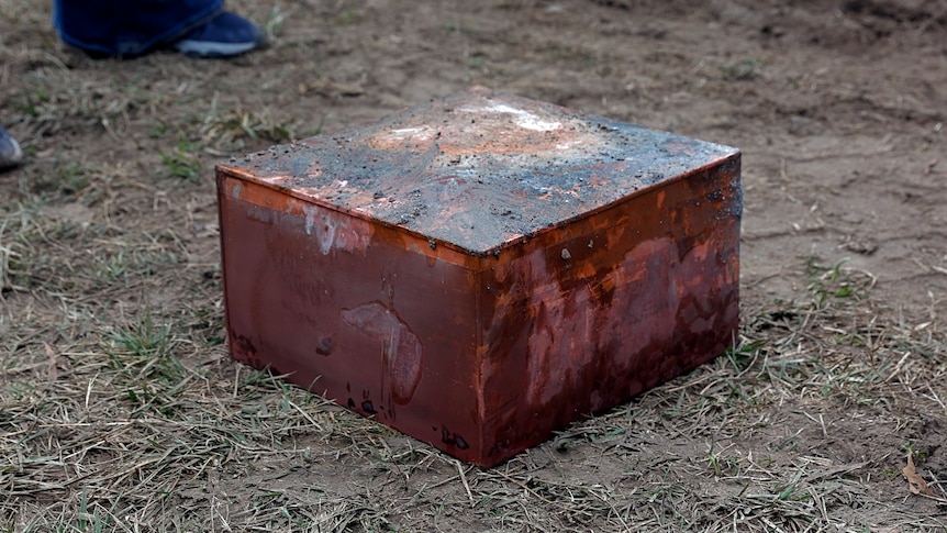 A brown box covered in dirt is on the ground.