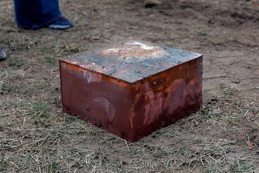 A brown box covered in dirt is on the ground.