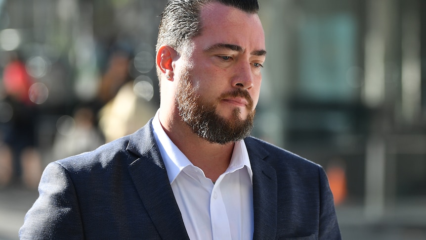 A man with a beard outside a court