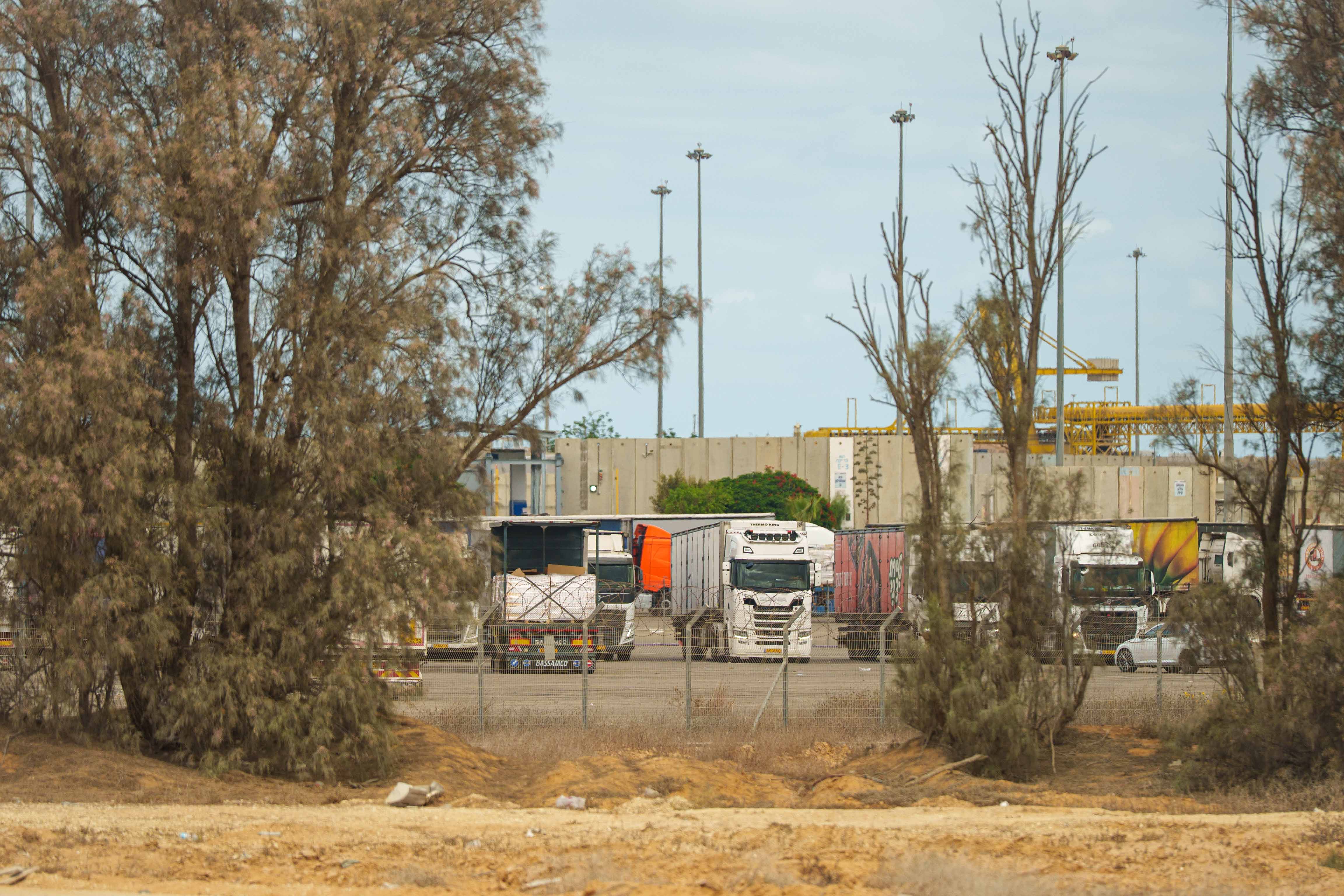 Trucks in a desert depot behind a chain-link fence.