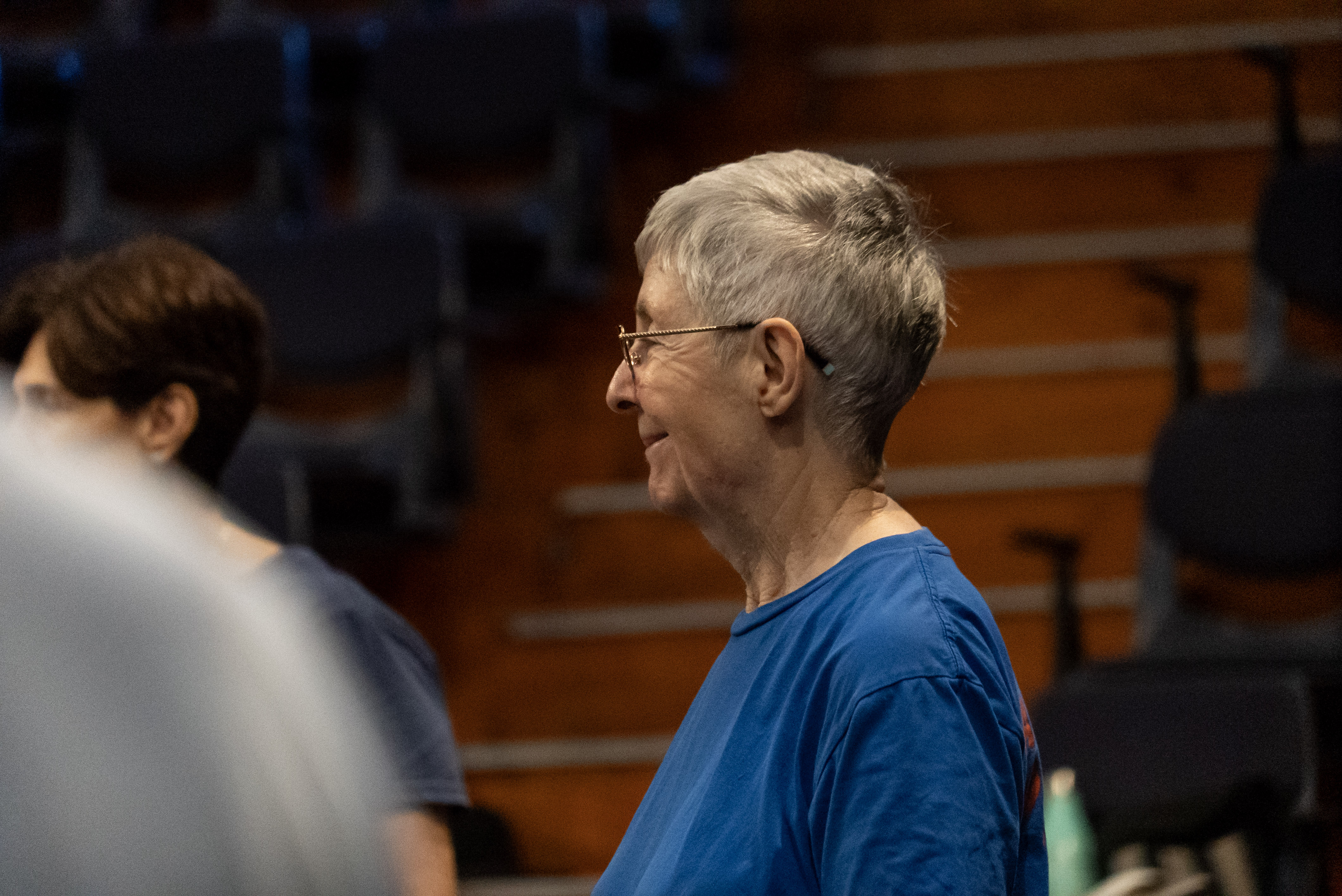 A woman in a blue shirt with grey hair shot in profile.
