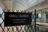 A black sign inside a shopping centre saying mall closed.
