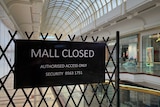 A black sign inside a shopping centre saying mall closed.